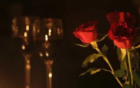 romantic setting with two wine glasses and a few red roses