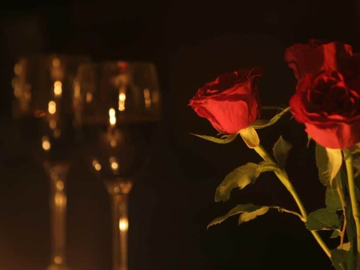romantic setting with two wine glasses and a few red roses